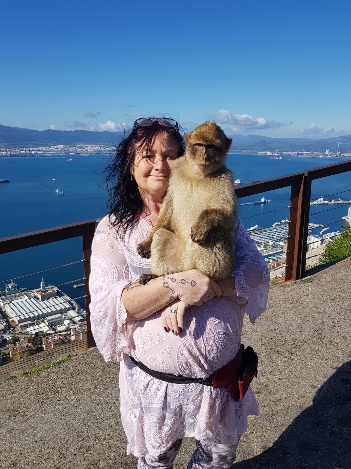 Visitor with a Barbary macaque overlooking Gibraltar and the bay from the Upper Rock